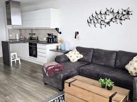 Un espacio habitable moderno con un sofá, una mesita de centro y una zona de cocina.