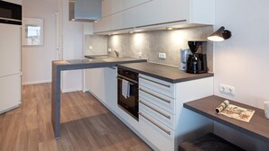 A modern kitchen with a built-in oven, a coffee maker, and a countertop with a magazine.