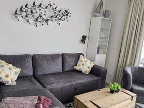 A modern living room with a sectional sofa, a coffee table, and decorative wall art. - 5 Star Holiday Home in Wendtorf (Wendtorf)