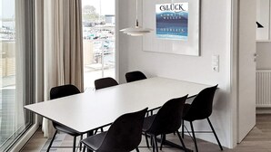 A modern hotel room with a large window, a white table, and black chairs.