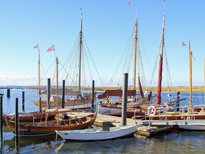 Un port de plaisance où sont amarrés différents types de bateaux, notamment des voiliers et des barques à rames.