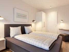 Un dormitorio moderno con cama, mesitas de noche, armario y un cuadro en la pared.