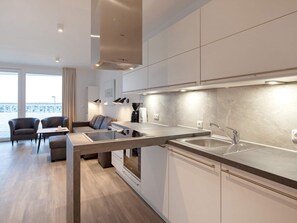A modern kitchen with a built-in oven, a sink, and a dining area with a table and chairs.