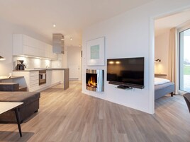 Una sala de estar moderna con chimenea, televisor de pantalla plana y comedor con cafetera.