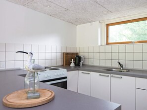 Une cuisine moderne avec des meubles blancs, une cuisinière et une fenêtre.