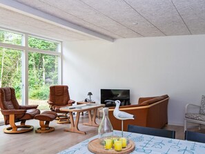 A modern living room with a large window, leather chairs, a wooden coffee table, a TV, and a table with drinks. - 4 Person Holiday Home in Ebeltoft (Ebeltoft)