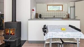 A modern kitchen with a central island, a built-in stove, and a dining area with a table set for two. - 4 Person Holiday Home in Ebeltoft (Ebeltoft)