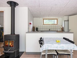 Una cocina moderna con una isla central, estufa integrada y un comedor con una mesa dispuesta para dos.