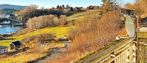 A scenic view from a balcony overlooking a river, a wooden deck, and a satellite dish.