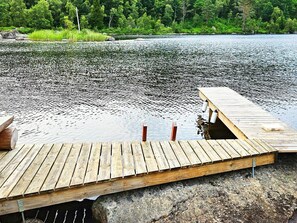Eine Holzsteg, der in einen See führt, mit bewaldeter Uferlinie im Hintergrund.
