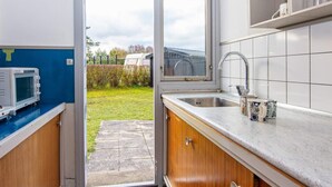 A compact kitchen with a built-in microwave, a sink, and a window overlooking a garden. - 6 Person Holiday Home in Glesborg (Glesborg)