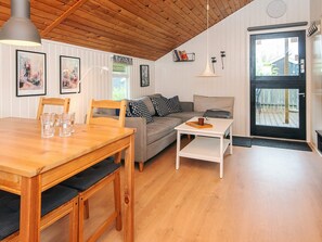 Een gezellige woonkamer met een houten eettafel, een bank en een witte salontafel.