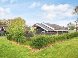 Een modern huis met een schuin dak, een omheinde tuin en een goed onderhouden tuin.