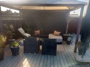 A covered outdoor seating area with a wooden deck, two sofas, and potted plants. - 4 Star Holiday Home in Otterup (Otterup)