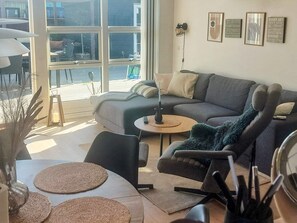 A modern living room with a sofa, armchair, and a dining table with placemats.