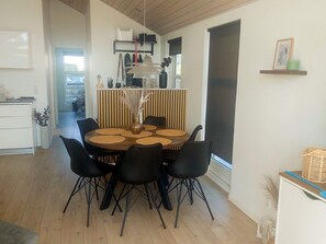 A dining area with a round table, black chairs, and a vase with dried plants.