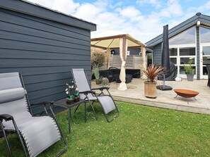 A patio area with outdoor furniture, a covered seating area, and a modern building with large windows. - 4 Star Holiday Home in Otterup (Otterup)