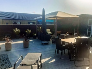 An outdoor patio area with a table and chairs, potted plants, and a covered seating area. - 4 Star Holiday Home in Otterup (Otterup)