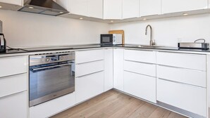Eine moderne Küche mit weißen Schränken, einem Edelstahlbackofen, einer Mikrowelle und einem Spülbecken.