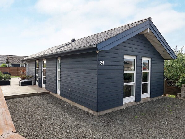 A single-story building with a dark siding exterior, a gabled roof, and a number '31' on the side.