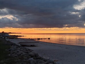 A beach with a rocky shoreline, a calm sea, and a sunset.