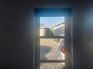 A view through a door with a clear sky, a building, and a car parked outside. - 4 Star Holiday Home in Otterup (Otterup)