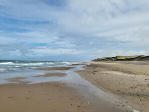 A beach with wet sand, waves, and a cloudy sky. - 6 Person Holiday Home in Thisted (Thisted)