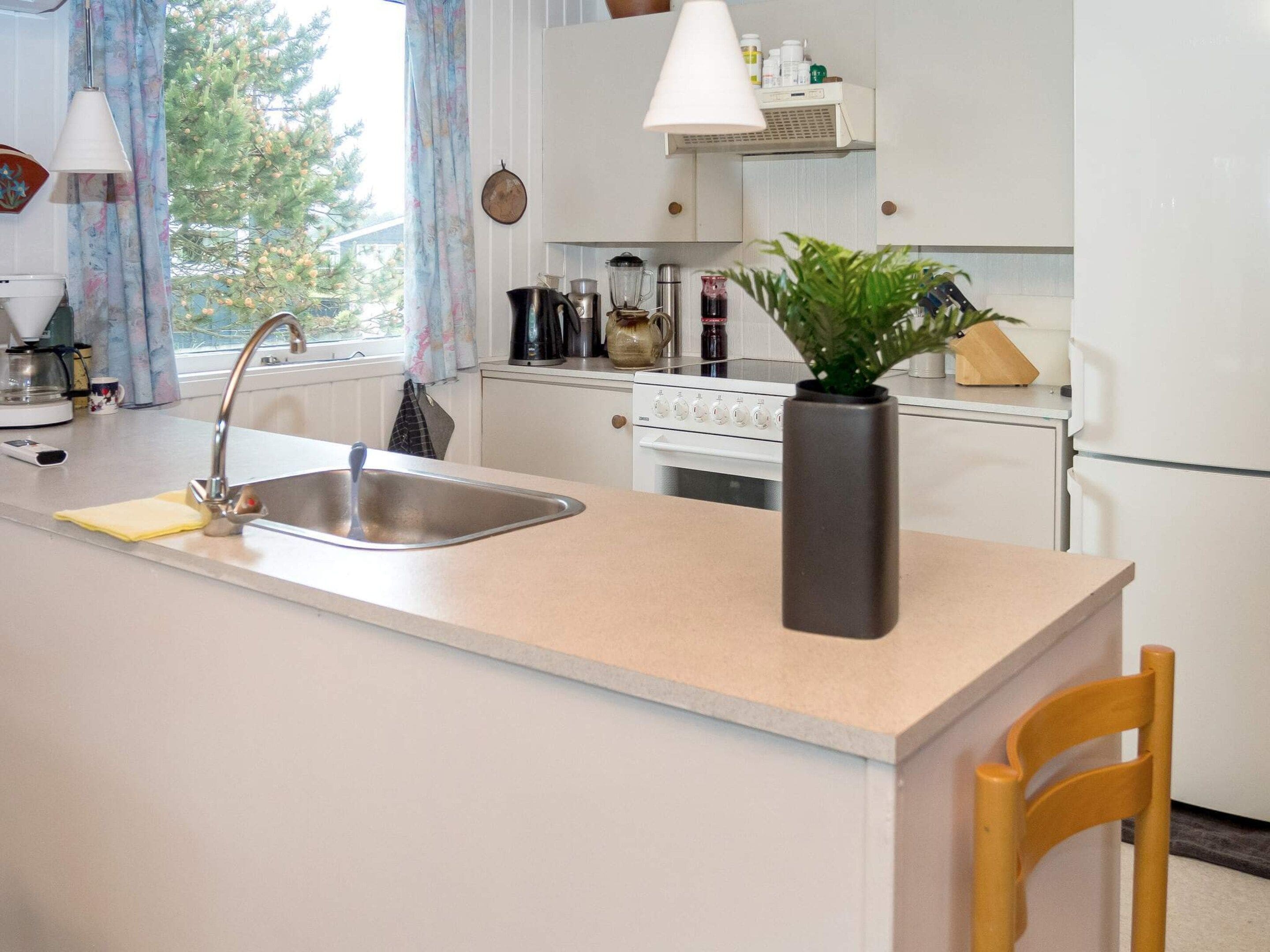A kitchen with a central island, a sink, a stove, and a refrigerator.