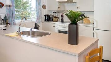 A kitchen with a central island, a sink, a stove, and a refrigerator.