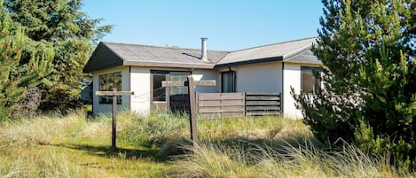 A single-story house with a sloped roof, a chimney, and a fenced yard.