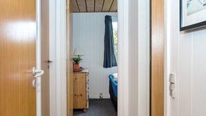 A narrow hallway leading to a room with a bed, a dresser, and a window with curtains. - 6 Person Holiday Home in Thisted (Thisted)