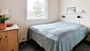 A bedroom with a bed, a dresser, a window, and a shelf with a picture. - 6 Person Holiday Home in Thisted (Thisted)