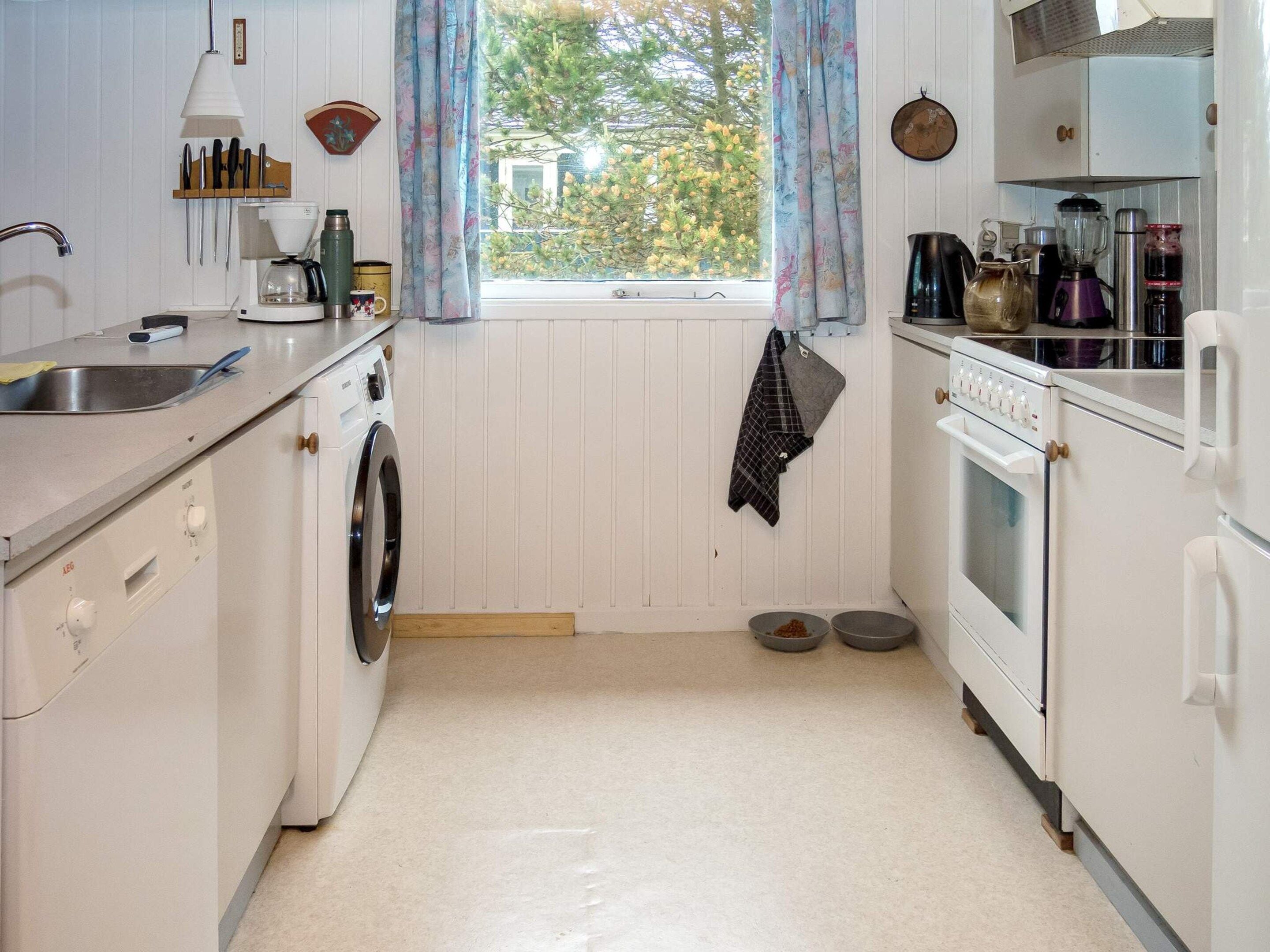 A compact kitchen with a washing machine, a stove, and a sink.