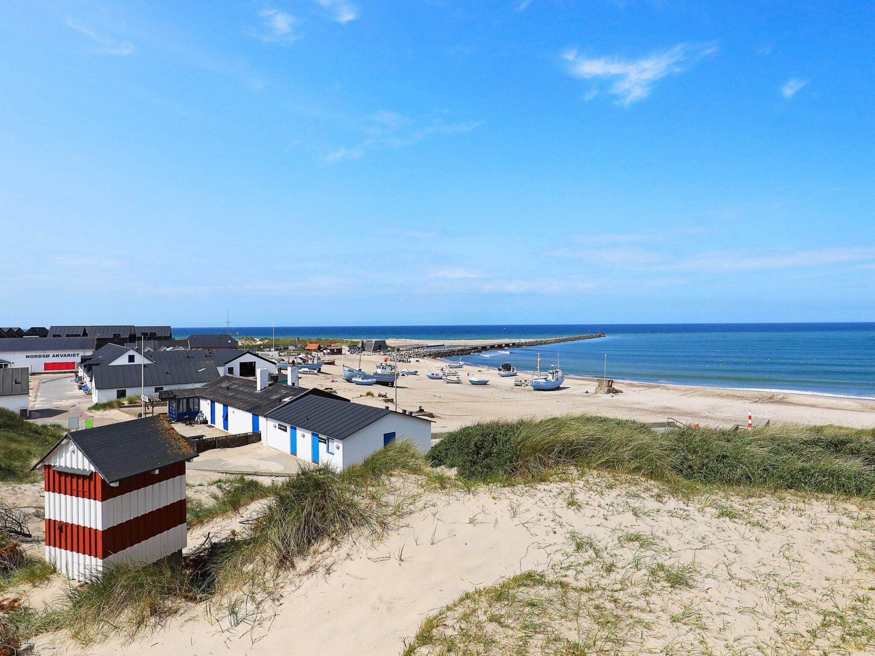 A coastal village with buildings, boats, and a sandy beach.