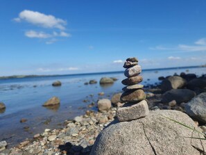 Kivikkoisella rannalla on kivistä kasattu keko, ja taustalla näkyy vesialue.