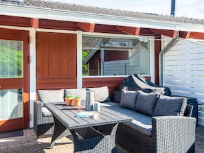 Un espace extérieur aménagé avec une table et des chaises, une fenêtre et une vue sur une maison.