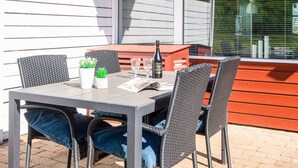 Eine Terrasse mit Tisch und Stühlen, einer Flasche Hardi-Wein und einer Zeitschrift.