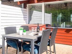 A patio with a table and chairs, a bottle of Hardi wine, and a magazine. - 4 Person Holiday Home in Aabenraa (Aabenraa)