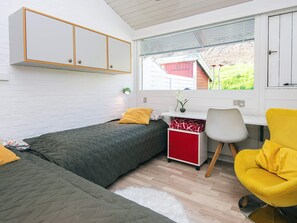Une chambre compacte comprenant deux lits simples, un bureau avec une chaise et une fenêtre donnant sur un espace verdoyant.