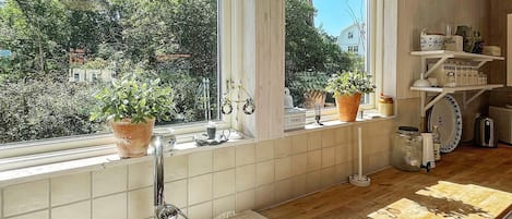 A kitchen with a large window, a sink, and a wooden countertop.