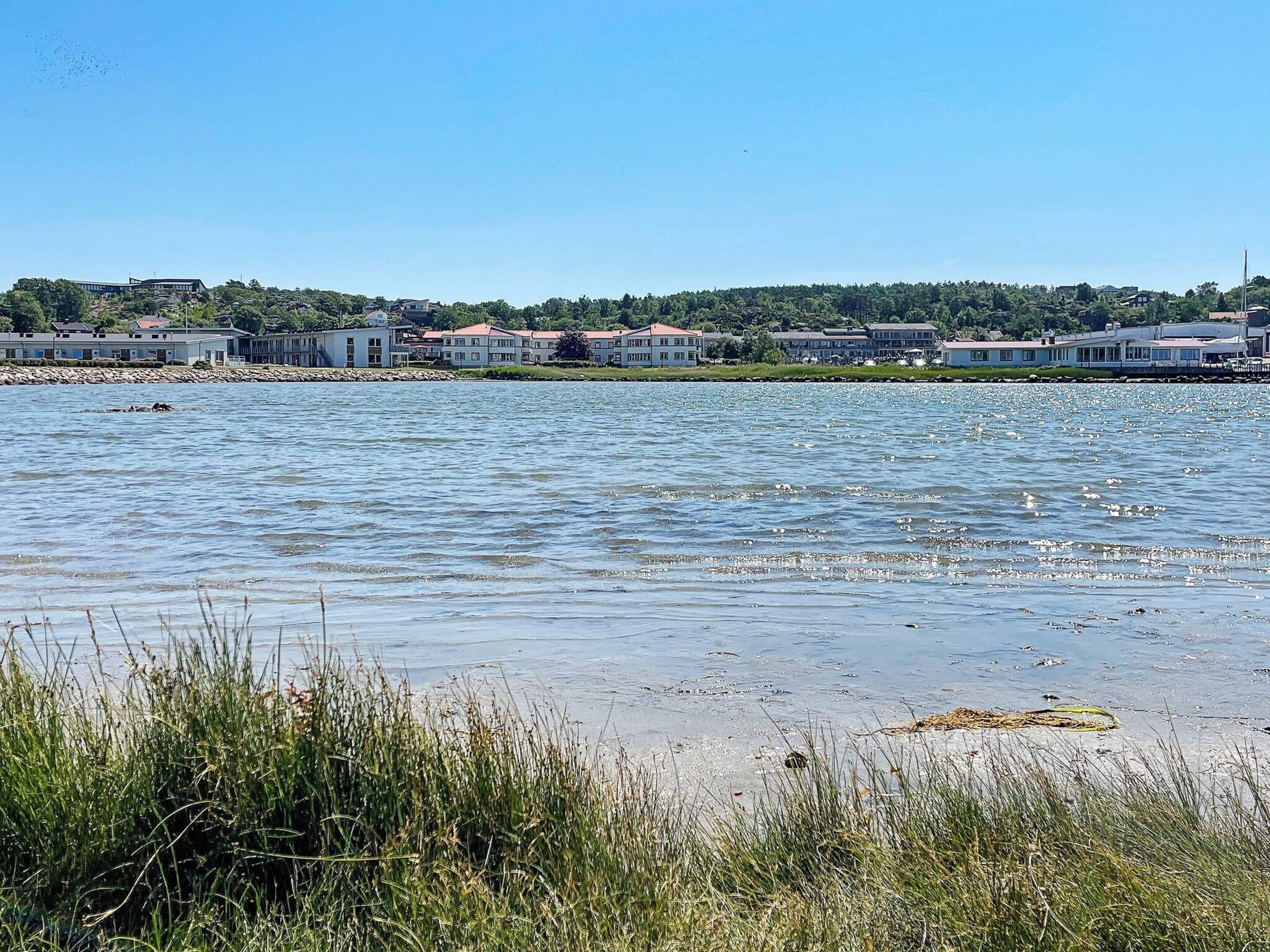 Um imóvel à beira-mar com uma fileira de edifícios, uma praia de areia e áreas ajardinadas.