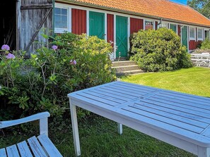 A wooden bench and a table in a garden area with a house in the background. - 4 Star Holiday Home in Ellos (Ellos)