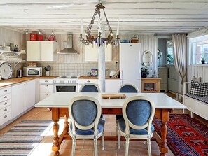 A kitchen with a dining table, chairs, a chandelier, and a refrigerator. - 4 Star Holiday Home in Ellos (Ellos)