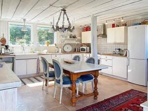 A kitchen with a dining table, chairs, and a chandelier. - 4 Star Holiday Home in Ellos (Ellos)