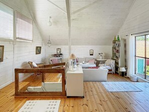 A cozy, well-lit room with wooden floors, a white sofa, a small table, and a bookshelf.