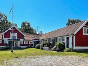 A row of red buildings with white trim, a flagpole, and a gravel path.