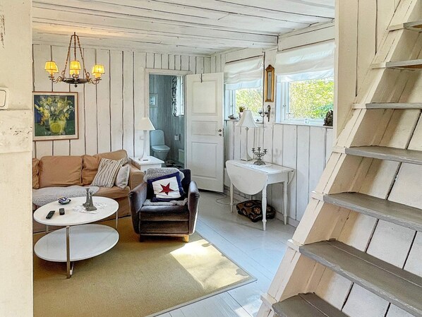 A cozy living room with a sofa, armchair, coffee table, and a staircase.