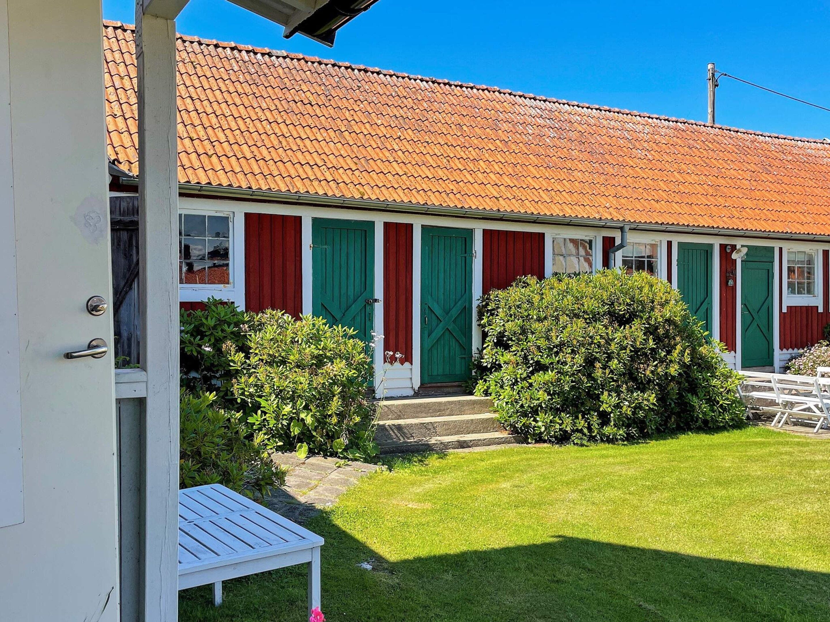 A single-story building with a red-tiled roof, green doors, and white walls.