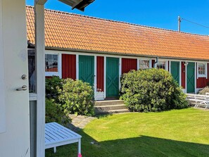 A single-story building with a red-tiled roof, green doors, and white-framed windows.