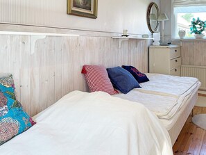 A bedroom with two beds, a dresser, a mirror, and a window with a view. - 4 Star Holiday Home in Ellos (Ellos)